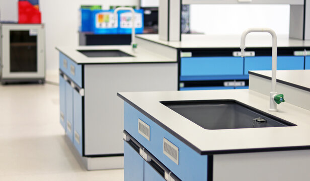 Blue sink with tap water set up into Bench lab in chemistry laboratory room. White Faucet with drop of water flowing into sink in laboratory, use for cleaning or washing hands prevent coronavirus.