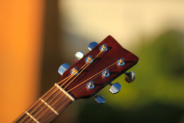 Guitar tuner. Wooden guitar on a natural blurred background. Guitar tuning. The guy tunes the guitar.