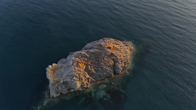 A circle shot of a rocky island during the sunset taken with a drone. Taken at the seaside village of Skala Eresou.