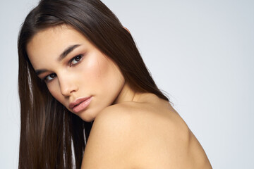 Naklejka premium Pretty brunette naked shoulders long hair close-up light background