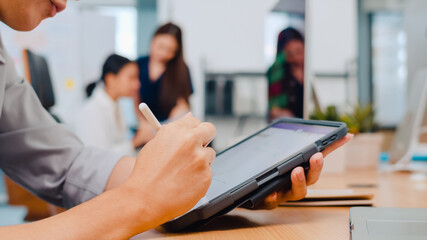Successful executive Asia young businessman smart casual wear drawing, writing and using pen with digital tablet computer thinking of inspiration search ideas working process in modern office.