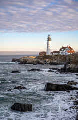 Fototapeta na wymiar An active lighthouse with ancillary buildings on the rocky coast of the Atlantic Ocean in Maine