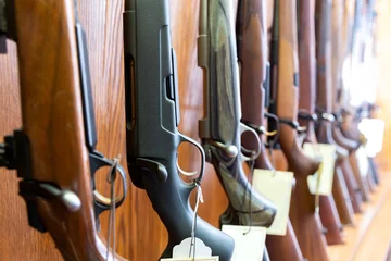 Poster Closeup of hunting and sporting rifles standing in row on gun shop showcase © JackF