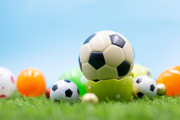 Soccer ball with Easter eggs are on green grass