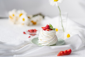 Meringue and whipped cream cake decorated with strawberries and mint on the table