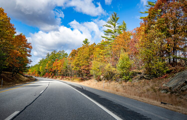 Landscape with a stretching highway road framed by autumnal scenic maples in Massachusetts