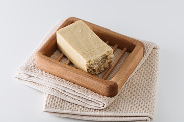 natural handmade soap on a wooden soap dish, side view, on a bath towel, light background