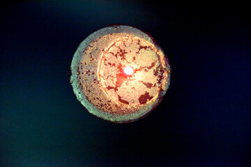 the view from the top at the top of the birning candle with golden layer ob the red wax