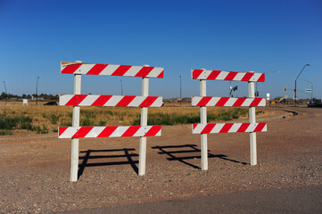 Two orange-and-white striped barricades placed on roadside gravel, marking restricted vehicle...