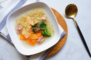 a plate of chicken and vegetable clear soup 