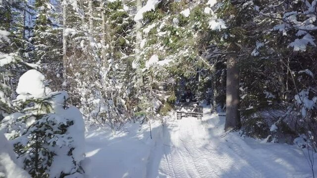 Low aerial pan of four wheeler driving through snowy forest, Finland