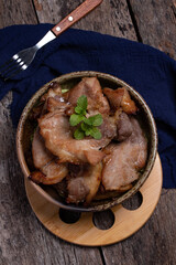 Roast pork in a ceramic cup on a wooden floor