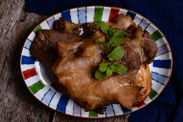 Roast pork in a ceramic cup on a wooden floor