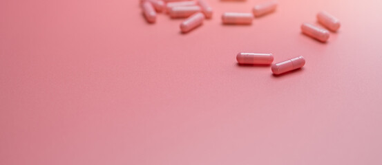 Pink capsules pill spread on pink background. Vitamins and supplements for healthy skin, collagen...