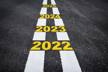 Number of 2022 to 2025 on asphalt road surface with marking lines, happy new year concept