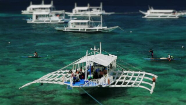 Snow-white diver boat swaying on sky-blue water under the coral reef on the Apo Island, Philippines