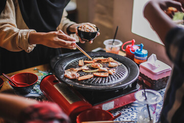 Hand of people cooking barbecue meat with chopsticks. Concept of summer party with families and friends