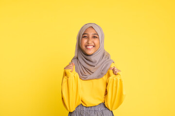 Fashion portrait of young beautiful asian muslim woman with wearing hijab isolated on yellow background