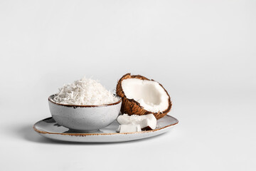 Plate with coconut flakes on white background