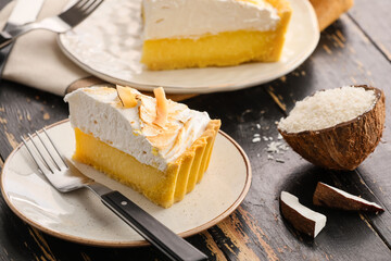 Plate with piece of tasty coconut pie on dark wooden background