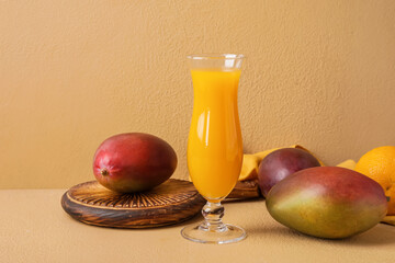 Glass of fresh mango juice on color background