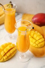 Glasses of fresh mango juice on light background