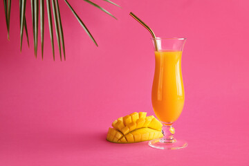 Glass of fresh mango juice on color background