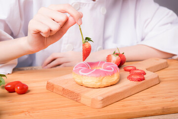 Young female chef is enjoying a pink dessert, ready to cook a new dish in the kitchen.
