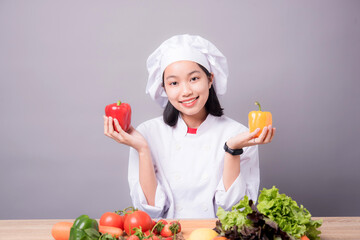 Portrait of a young Asian female chef ready to cook a new dish in the kitchen. 