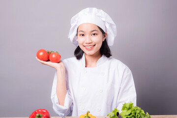 Portrait of a young Asian female chef ready to cook a new dish in the kitchen. 