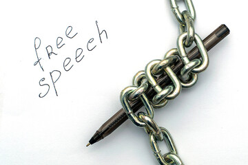 a fountain pen wrapped in an iron chain on sheets of white paper with the inscription free speech the concept of freedom of speech