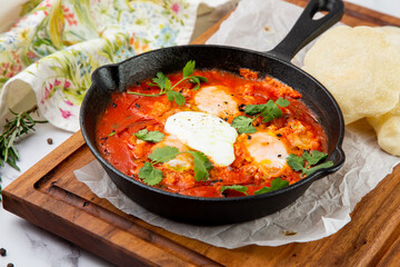 shakshuka - scrambled eggs with herbs, beans and tomatoes in a skillet with lean crispbread