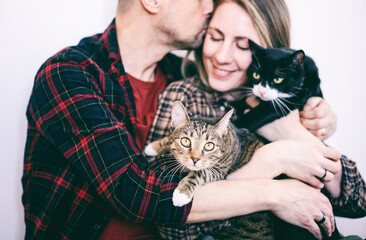 Beautiful happy adult married couple hugging with cats, close-up portrait