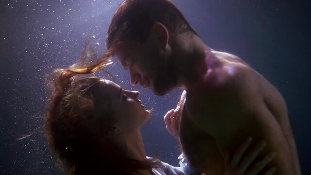tender loving couple is bathing in swimming pool, underwater shot of diving man and woman