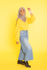 Fashion portrait of young beautiful asian muslim woman with wearing hijab isolated on yellow background.