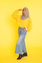 Fototapeta premium Fashion portrait of young beautiful asian muslim woman with wearing hijab isolated on yellow background.