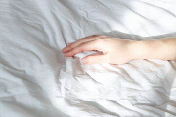 Morning in bed, a woman's hand in the sun. A slow awakening.