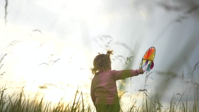 Happy little girl with a toy in the park. A child with a colored toy in the park. Happy little girl is playing in the park. Close up portrait of a girl with a toy in her hand. Child dream