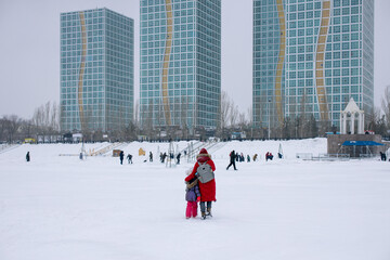 Mother and child walking on a snow-covered frozen river. Nur-Sultan, Kazakhstan.