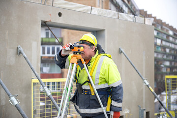 One real senior surveyor worker working with theodolite or tacheometer transit equipment at...