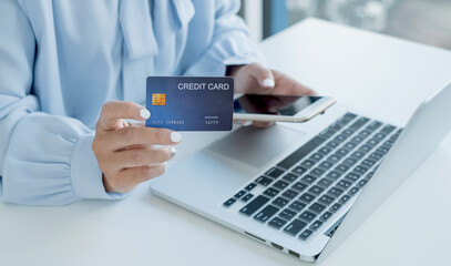 The businesswoman's hand is holding a credit card and using a smartphone for online shopping and internet payment