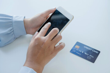 The businesswoman's hand is holding a credit card and using a smartphone for online shopping and internet payment