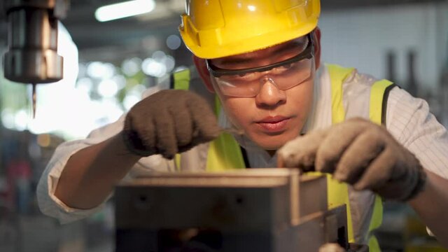 Manufacturing worker. Asian mechanical engineer operating industrial lathe machine.