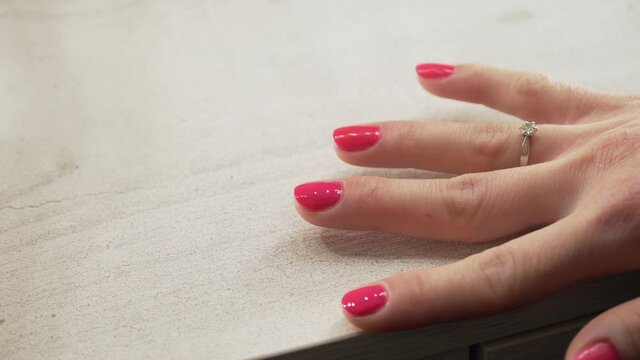 a young European girl paints her nails with pink nail polish