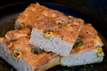 Pieces of fresh soft moist sourdough focaccia with green olives