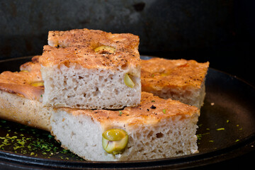 Pieces of fresh soft moist sourdough focaccia with green olives
