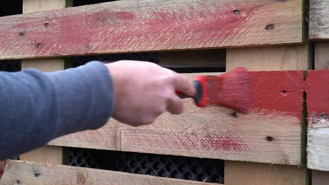 Brett mit roter Farbe anstreichen