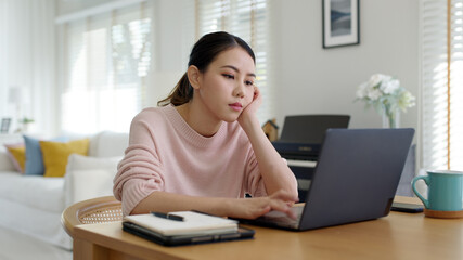 Back rear view young asian woman employee work from home using computer notebook videocall meeting...