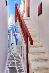 Traditional narrow cobbled streets, beautiful alleyways of Greek island towns. White houses, flower pots, balconies, stairs and doors. Mykonos, Greece