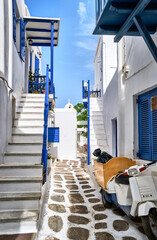 Beautiful traditional narrow streets, cobbled alleyways of Greek island town. Whitewashed houses, blue balconies, parked old scooter. Mykonos, Greece.